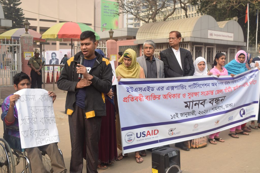 Young man holding microphone speaks standing in front of human chain